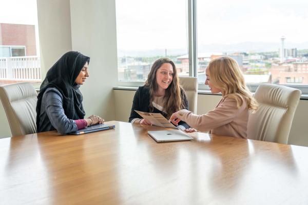 three business school students conversing in a meeting room